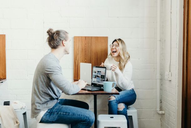 A man and woman sharing coffee and working on their laptops